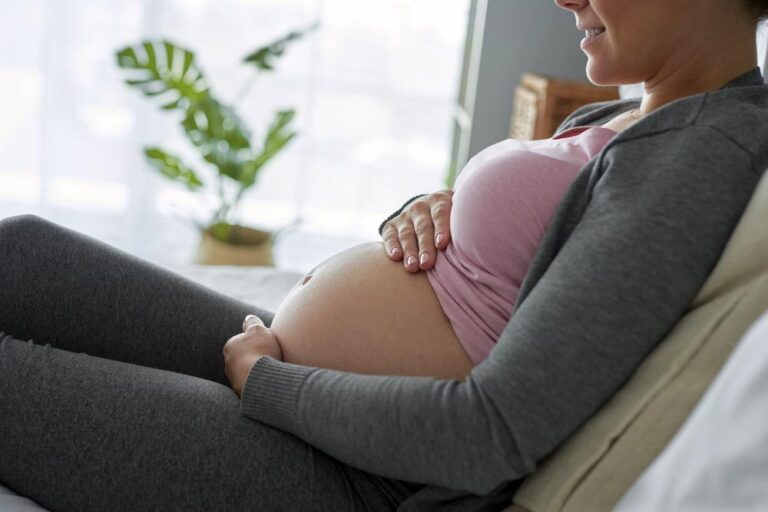 Profile view of cheerful pregnant woman in bed