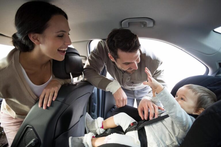 Parents securing baby in the car seat in their car